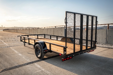 A rear view of a utility trailer with a wooden deck and black metal mesh sides.