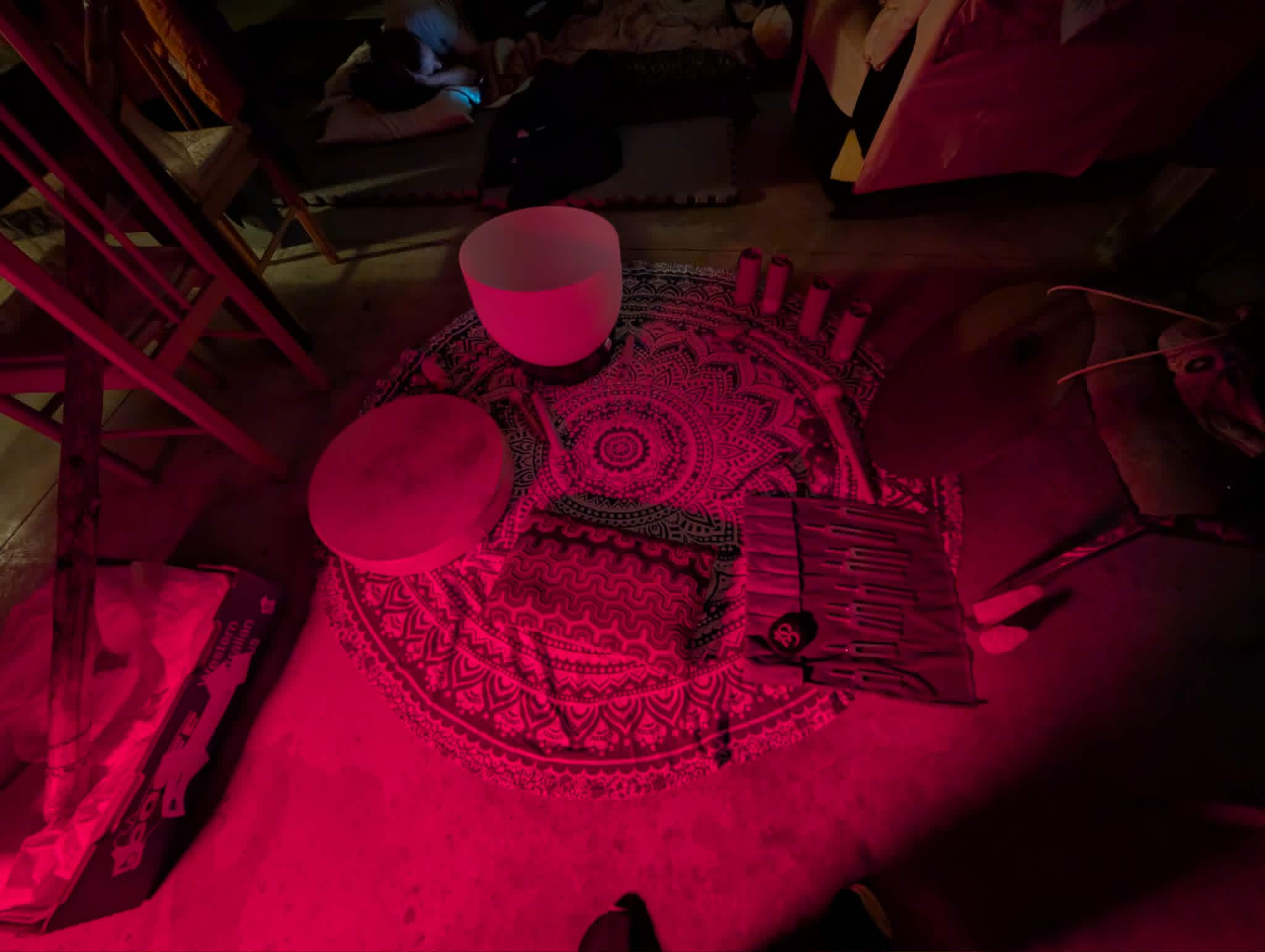 Sound immersion setup with crystal singing bowls under atmospheric pink light