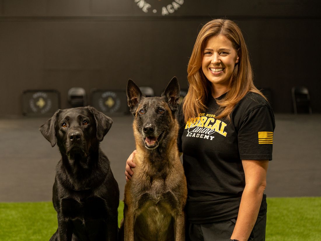 Sam Lee at the academy with her black labrador and her malinois sitting beside her