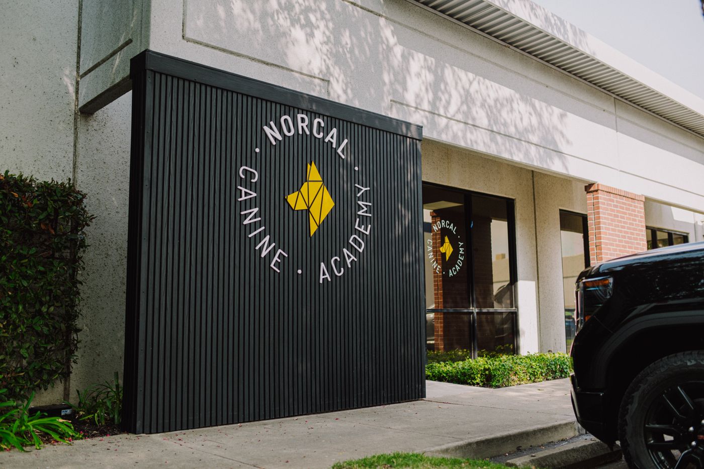 The front of the NorCal Canine Academy building on Lathrop Way, black frontage with the academy roundel