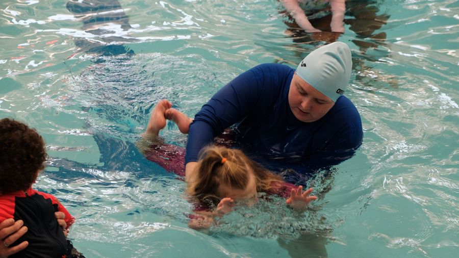 Instructor helping a young swimmer glide forward in the water