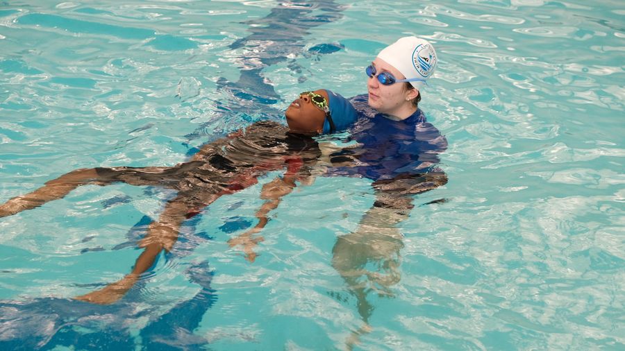 Child practicing a back float with an instructor