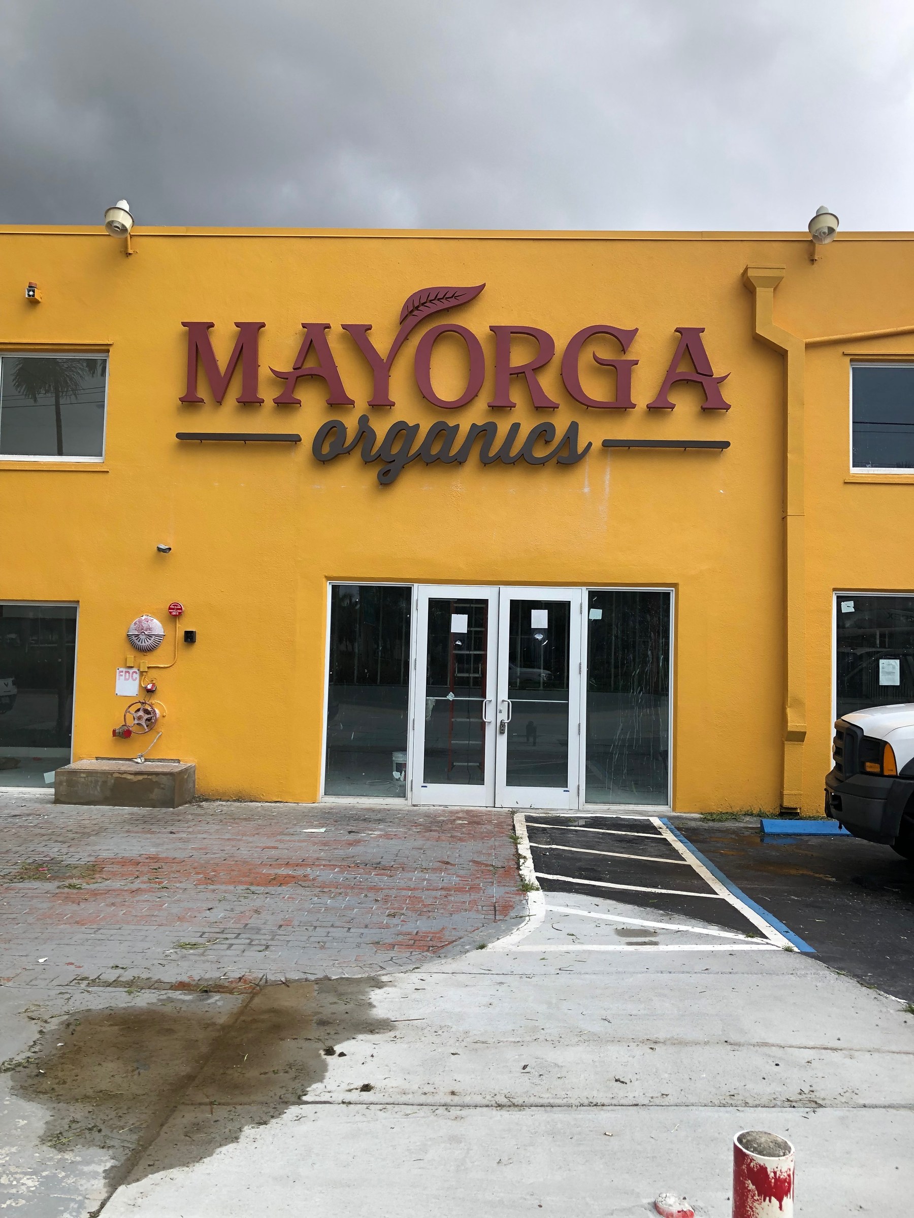Mayorga Organics channel letter sign on a yellow commercial building