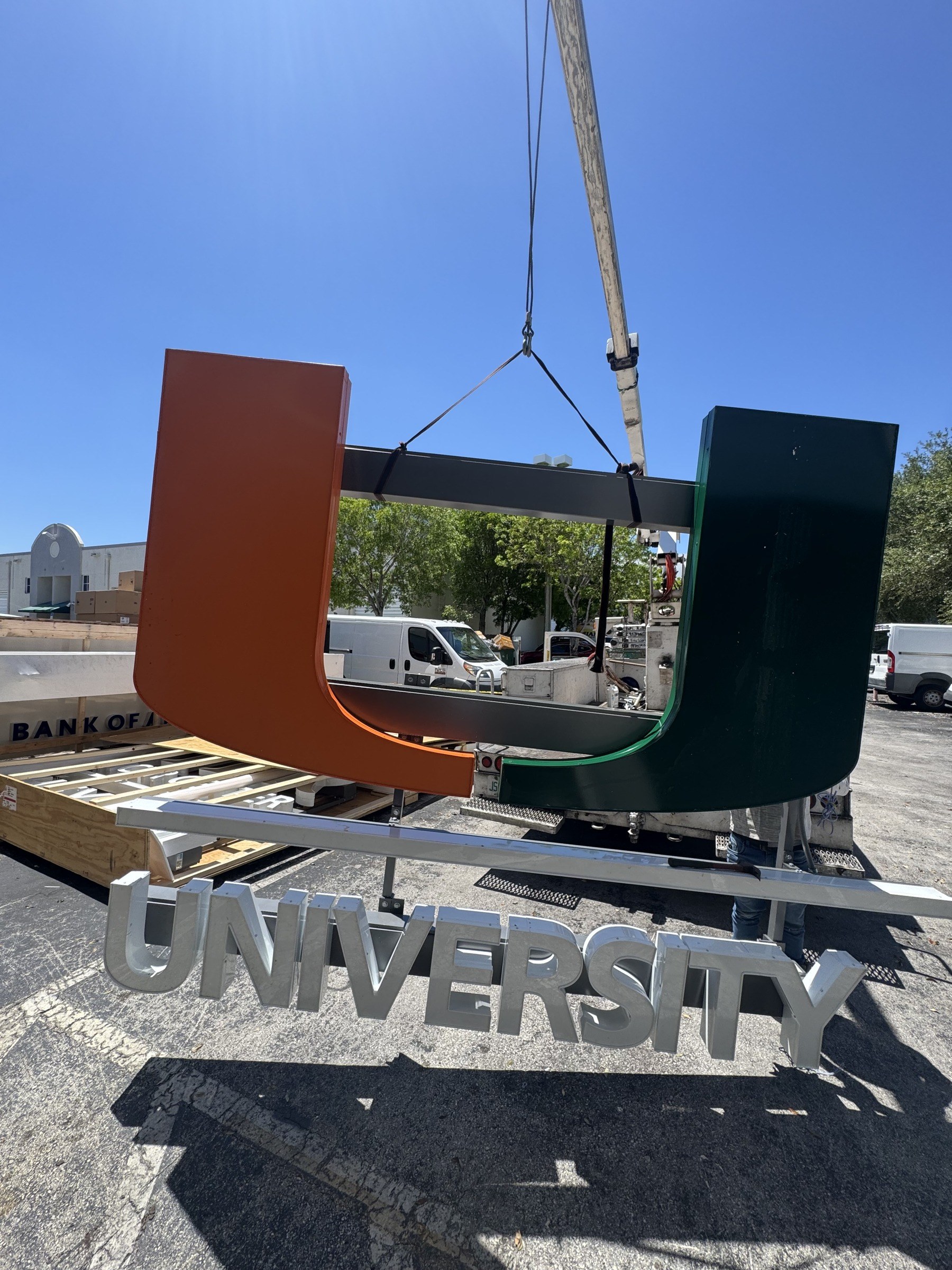 Crane lifting large fabricated letters into place on a job site