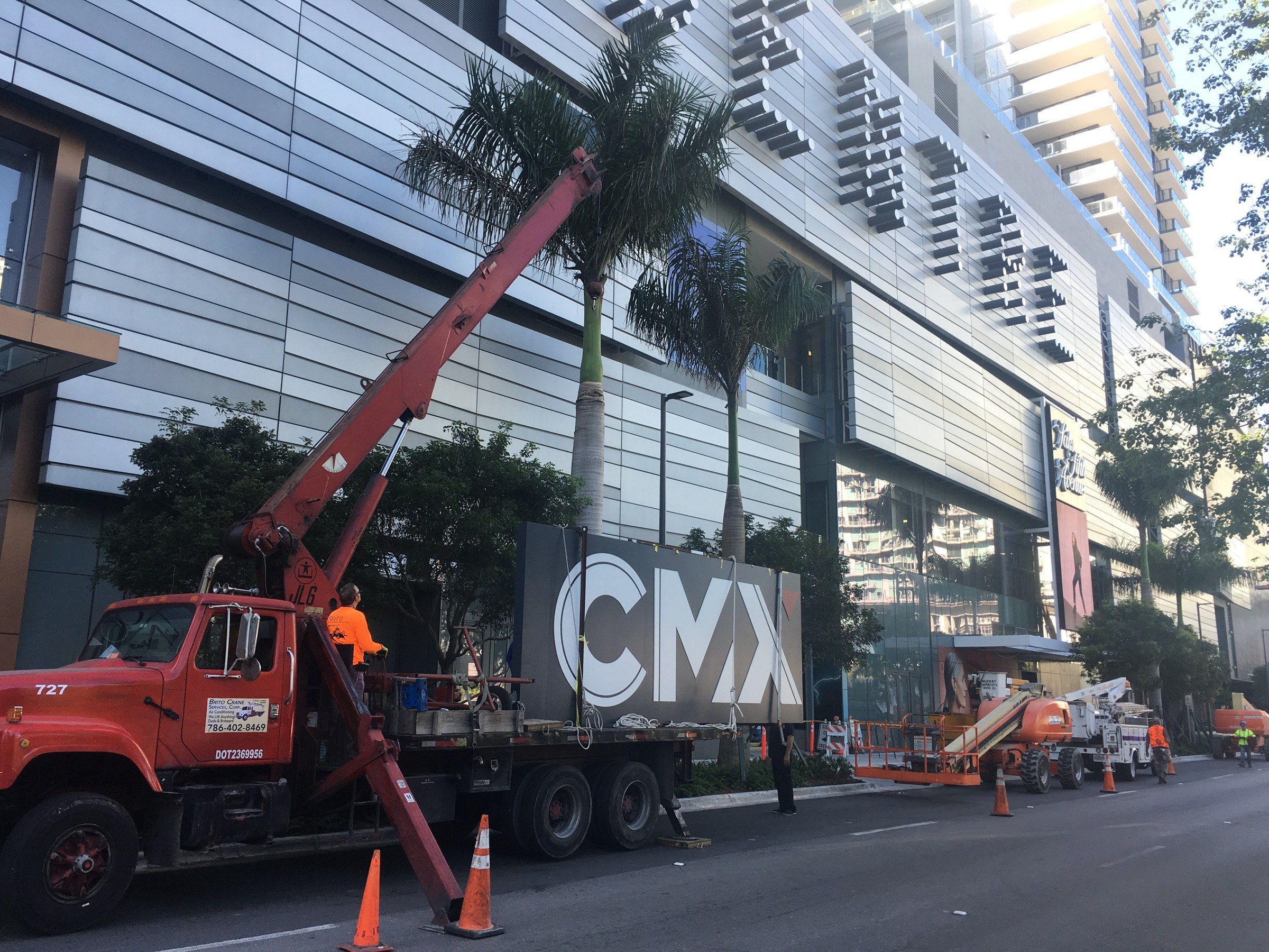 Corporate Signs crane truck and crew setting large illuminated letters on a high-rise building