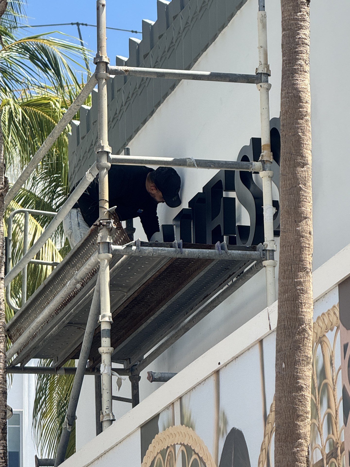 Corporate Signs installers mounting black channel letters on a building from scaffolding