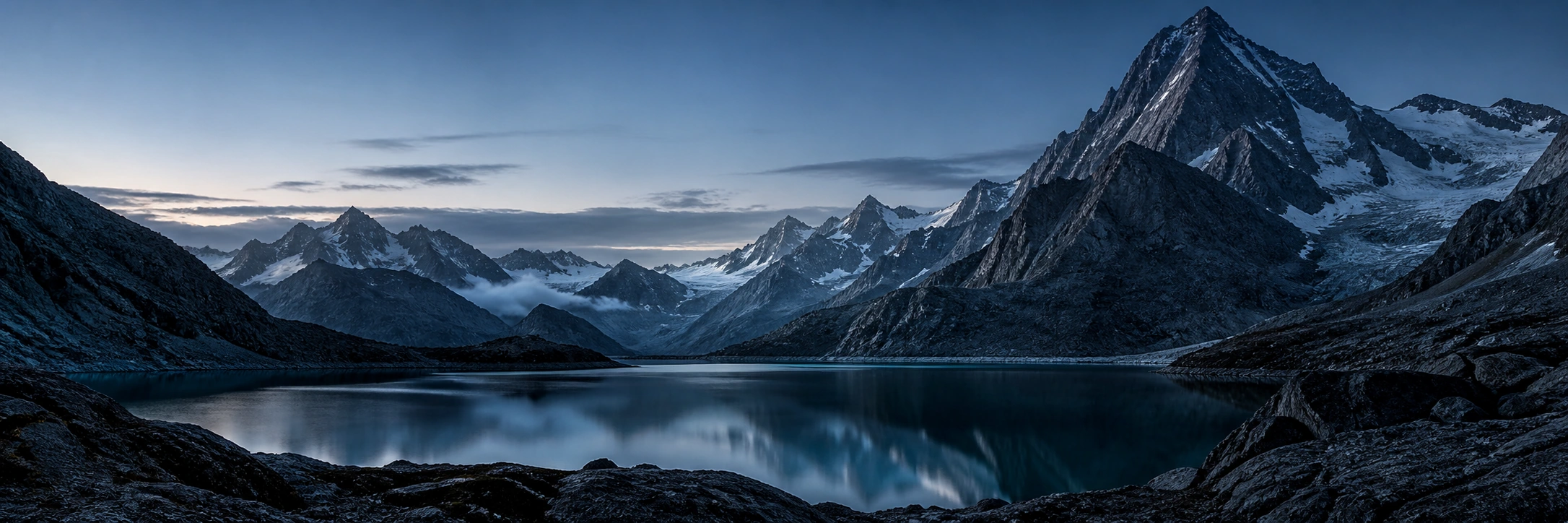 A still alpine lake below a sharp mountain ridge