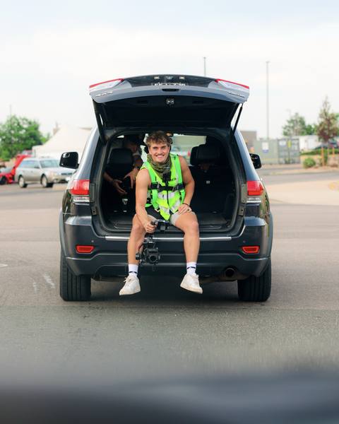 A child sitting in the open back of a parked SUV.