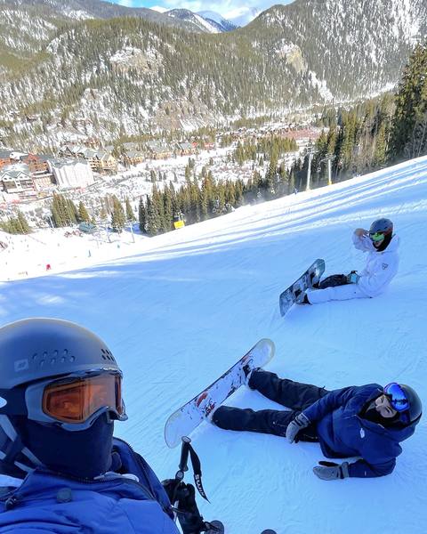 Three people taking a break on a snowy mountain slope.