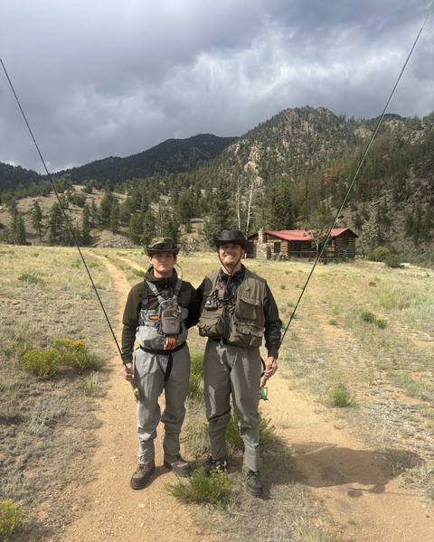 Two anglers standing together with fishing rods on a mountain trail.