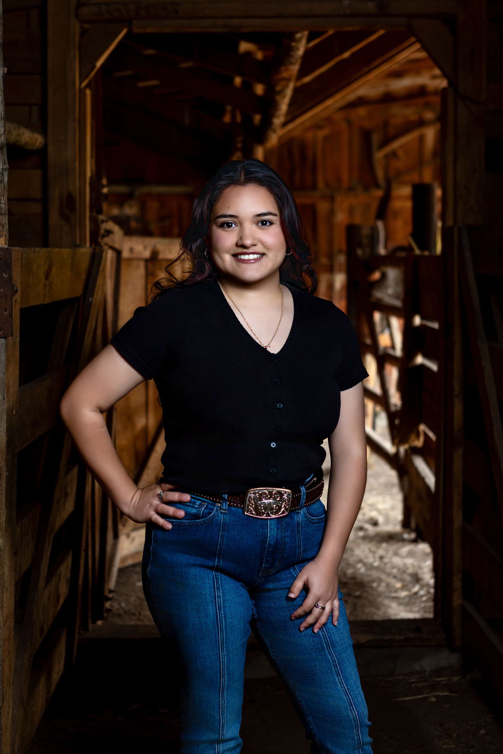 Senior girl in black top and jeans posing in a rustic barn loveland colorado senior portrait photographer