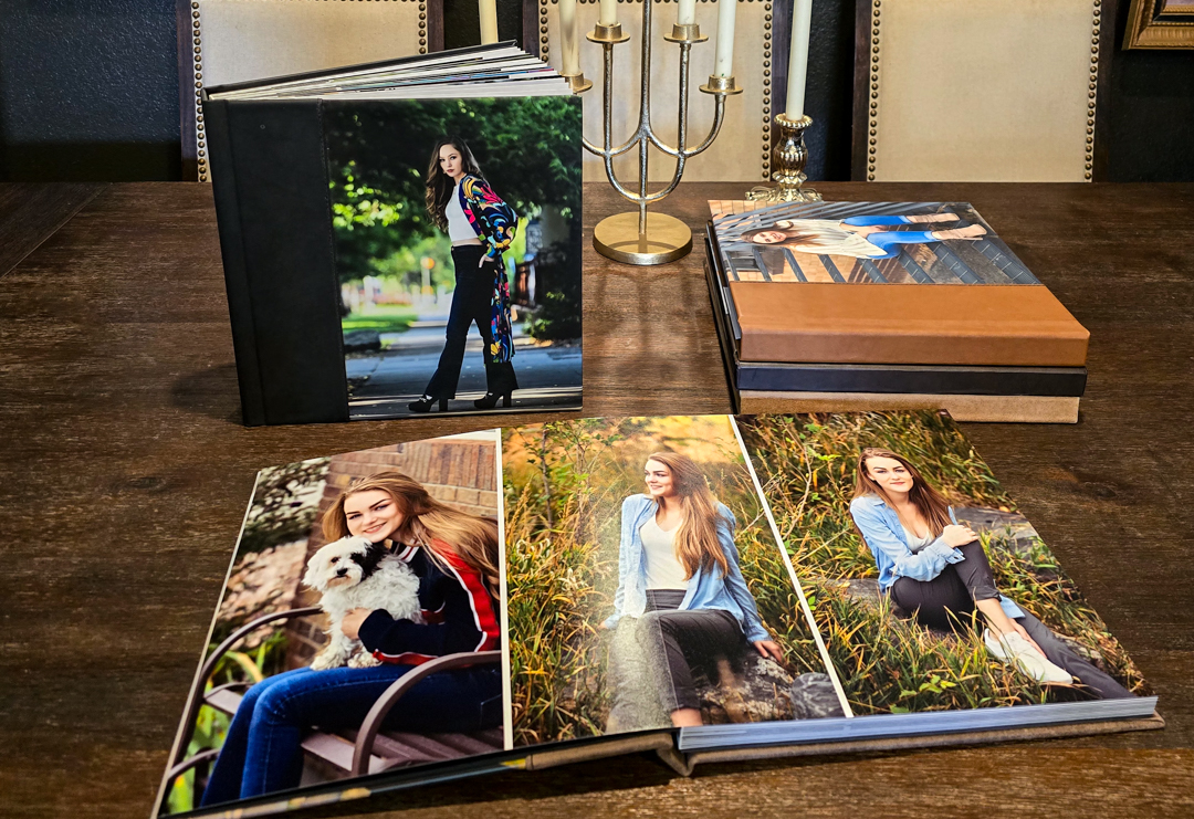Senior portrait heirloom albums open on a wood table showing high school senior photos Northern Colorado photographer