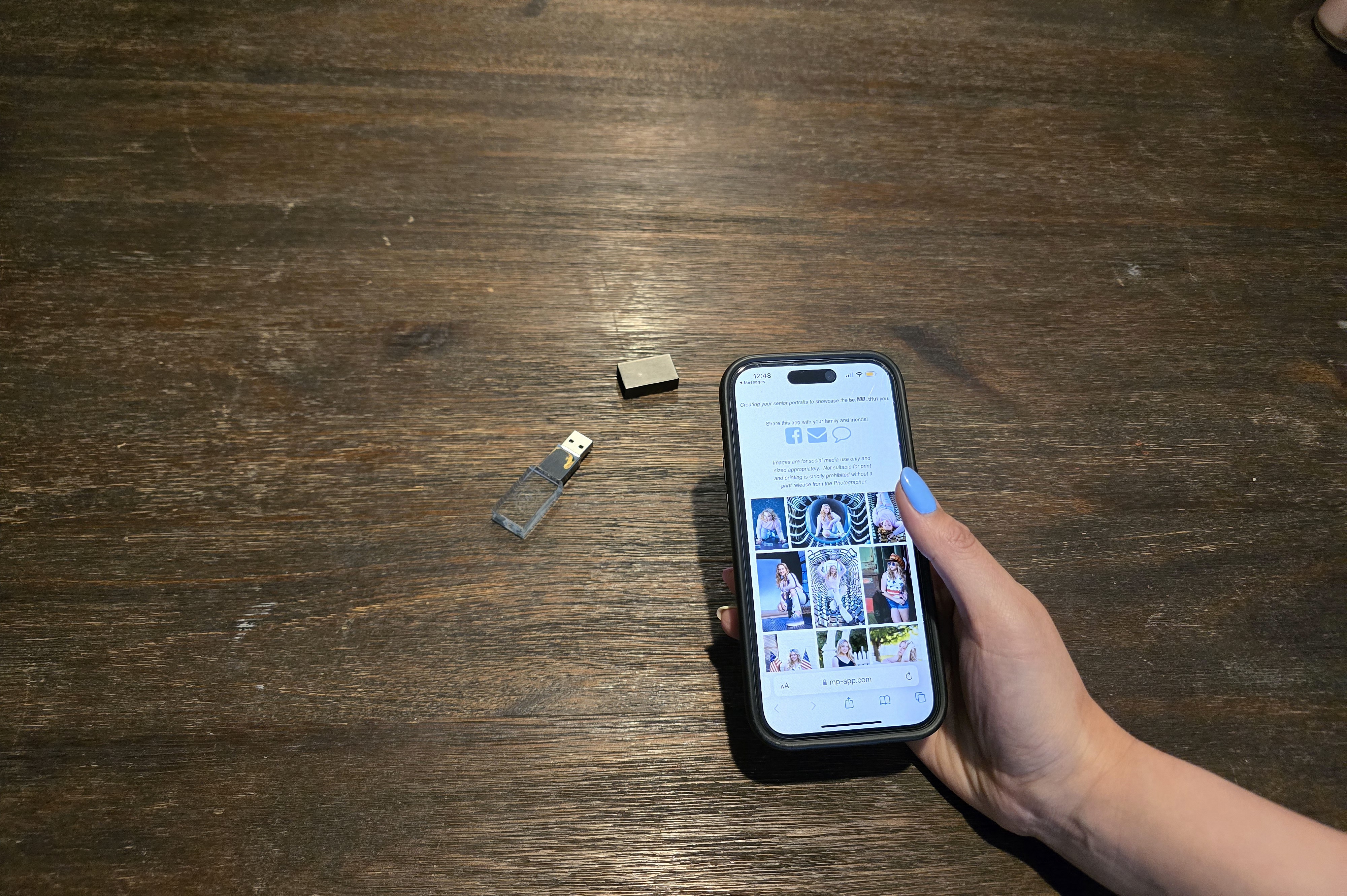 Crystal USB drive and smartphone displaying senior portrait gallery app Northern Colorado photographer