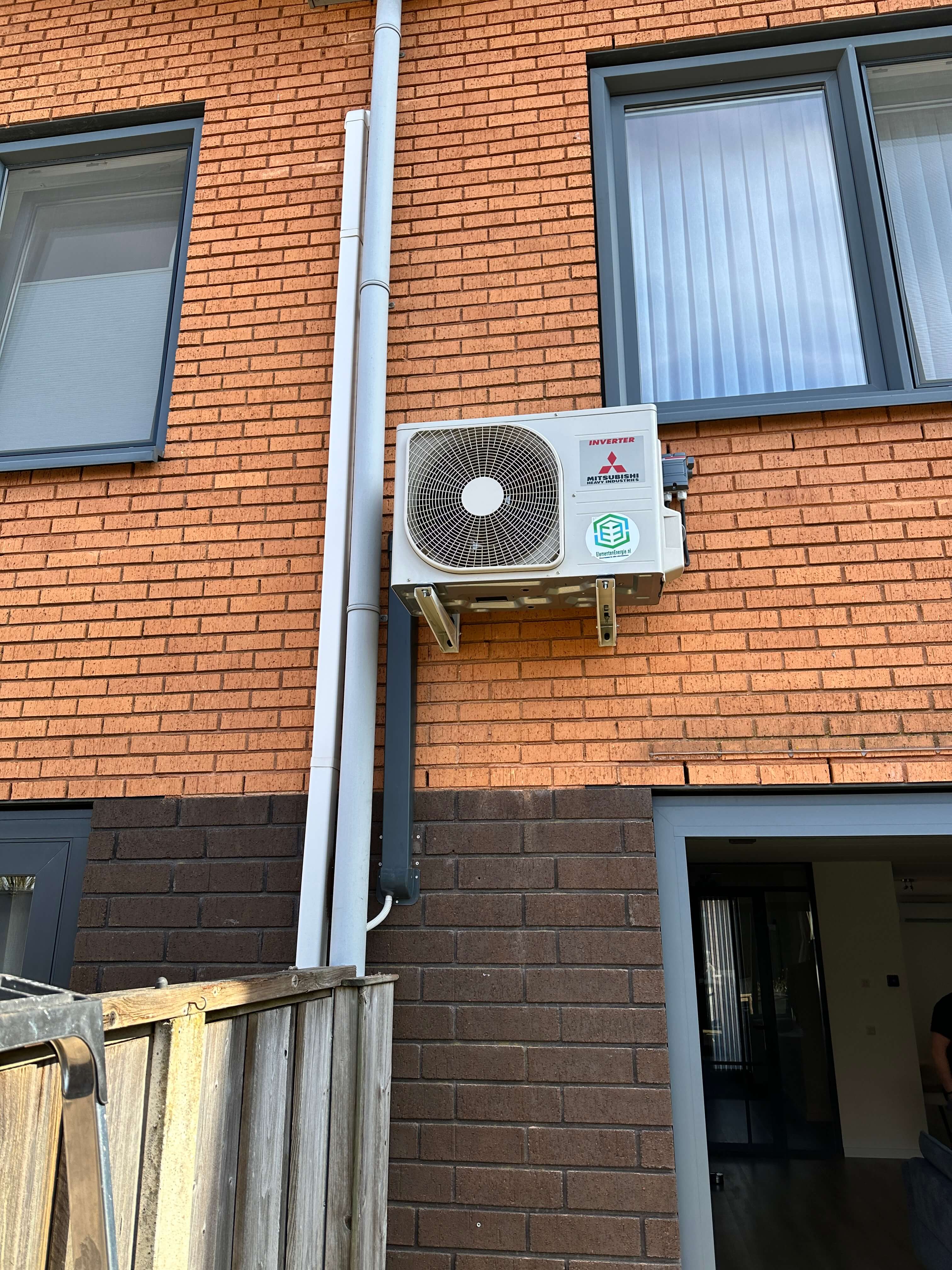 Witte airco buitenunit op houten wand