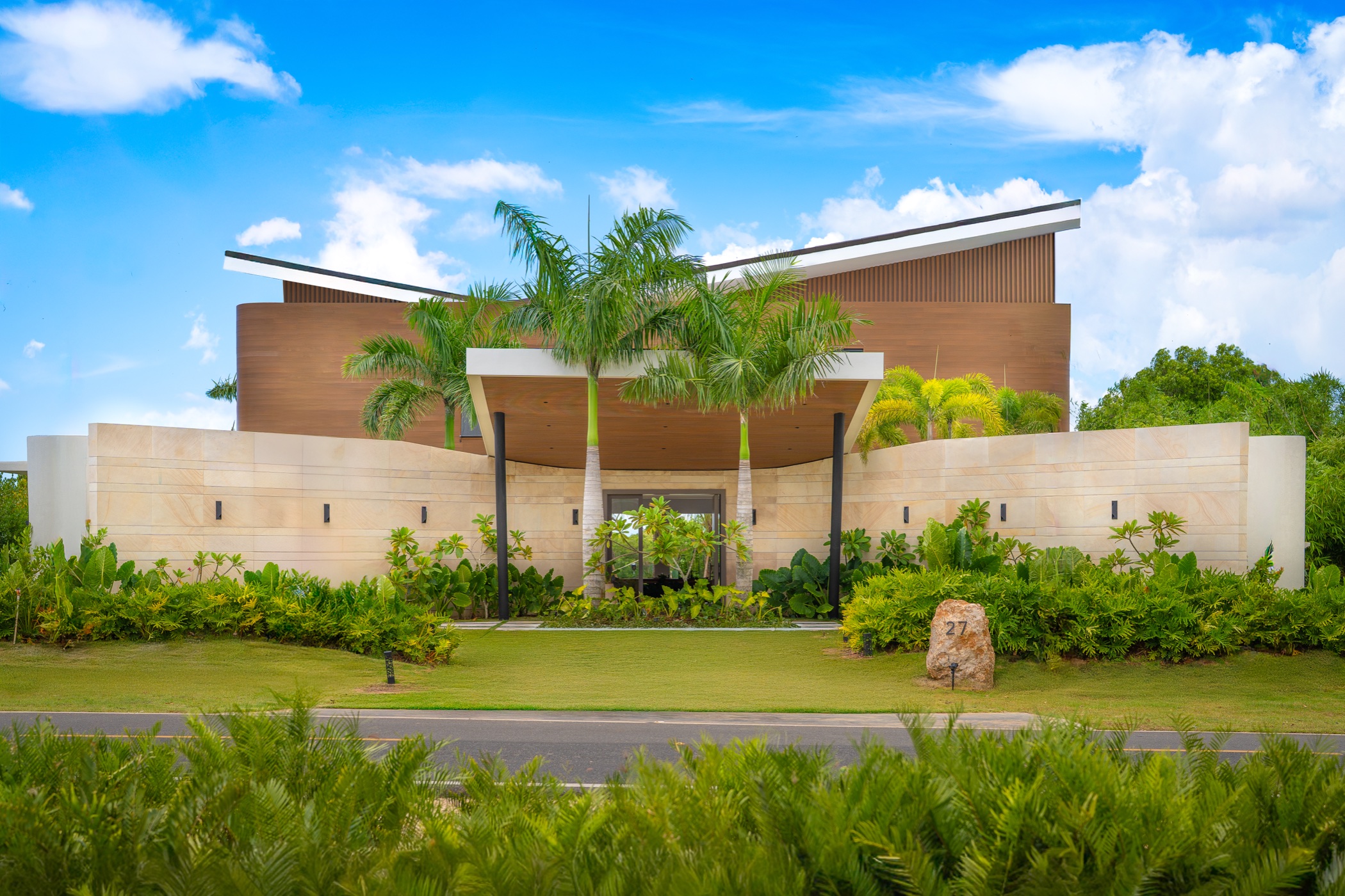 Villa Veintisiete facade in daylight, stone wall and royal palms, Casa de Campo