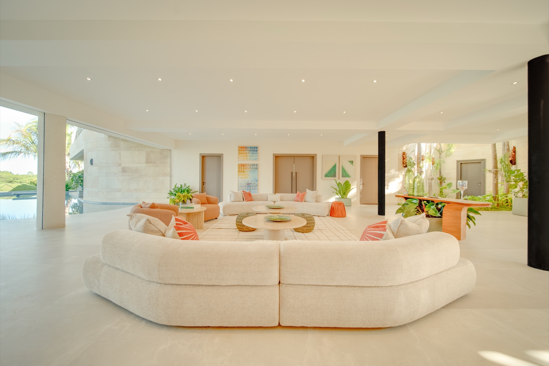 Great room with curved cream sectionals and pool view