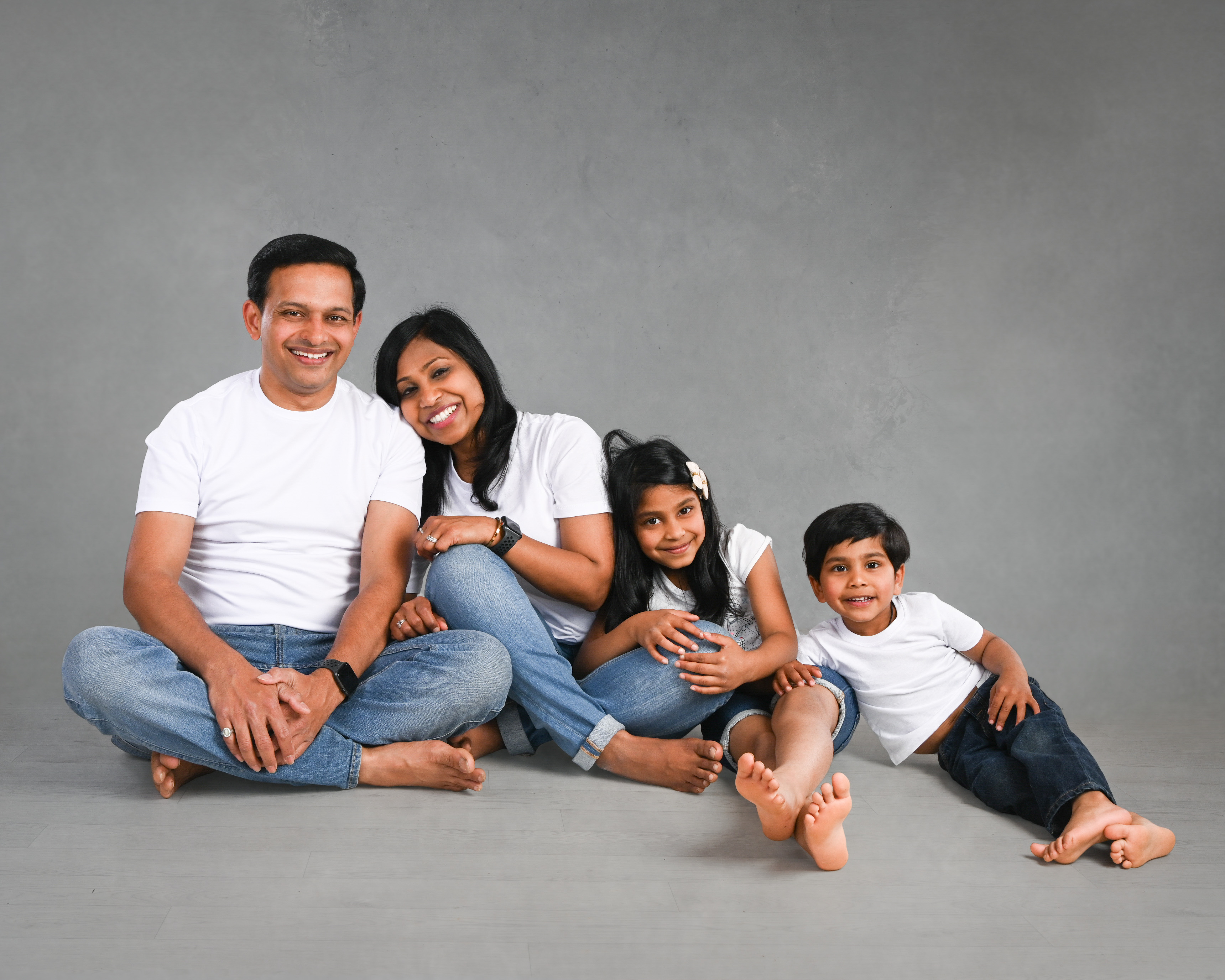 Dad, mother and 2 children sitting together in a studio for portrait experience in Watford near London
