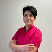 Aesthetic clinic owner smiling warmly inside her treatment room, wearing a professional uniform