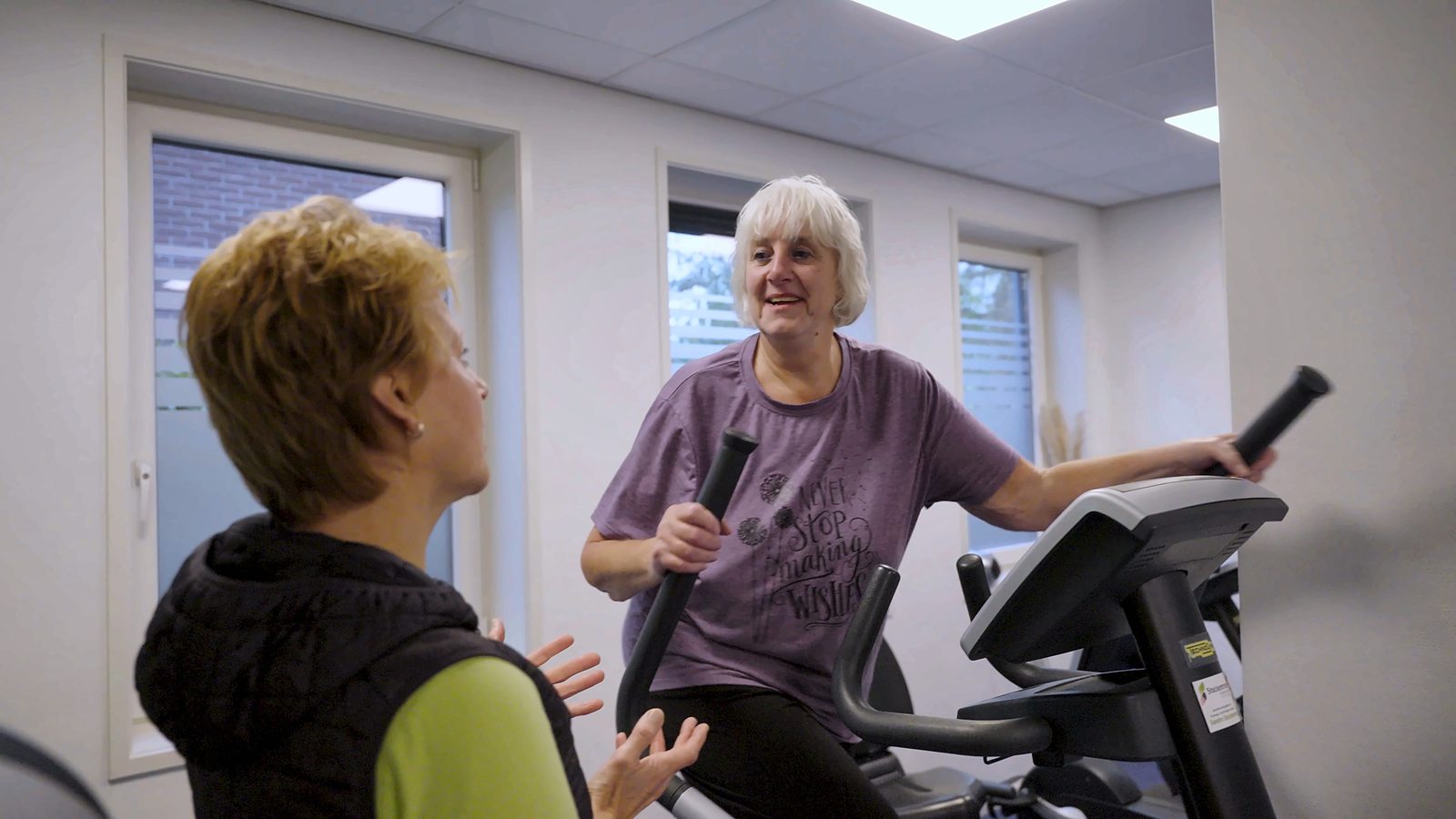 Sandra en een lachende pati&euml;nt op de crosstrainer