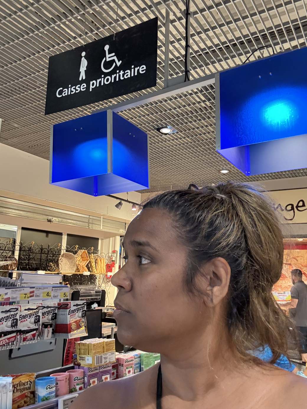 Priscilla sous le panneau caisse prioritaire d'un supermarché, carte prioritaire et handicap invisible » 