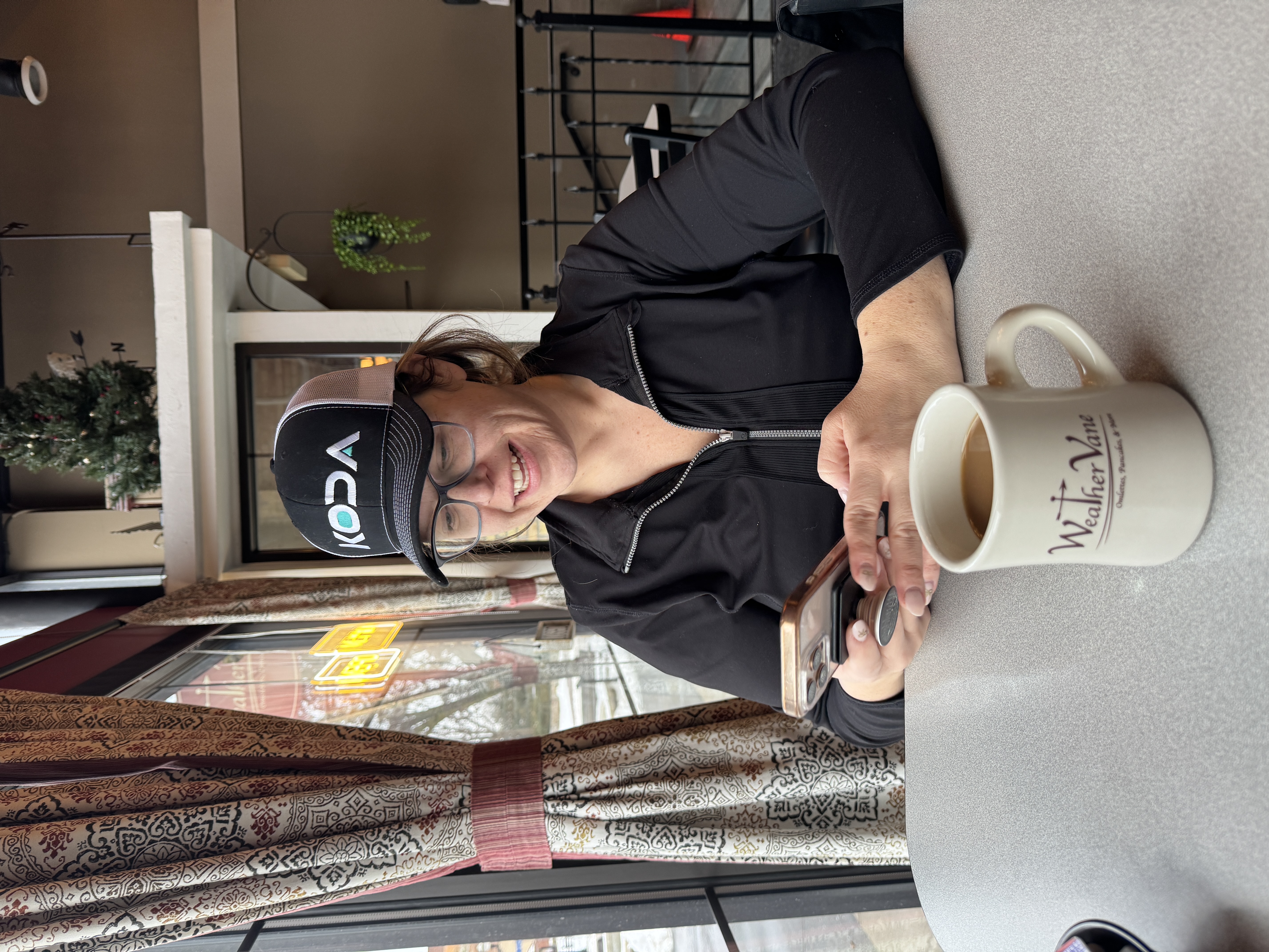 Professional casually using her phone at a coffee shop — content creation that fits into your life
