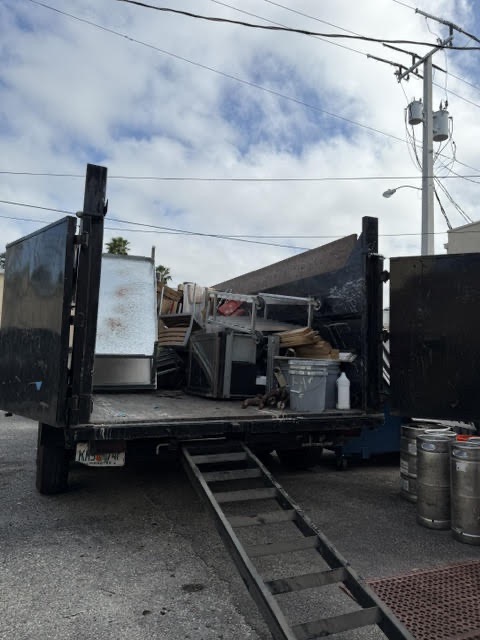 Dump trailer loaded with construction debris, furniture, and cleanup waste during a hauling and demolition cleanup project.