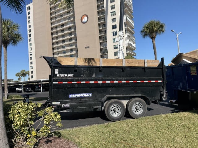 Black dumpster trailer parked outside a high-rise condo building in Sarasota, Florida for a dumpster rental service.