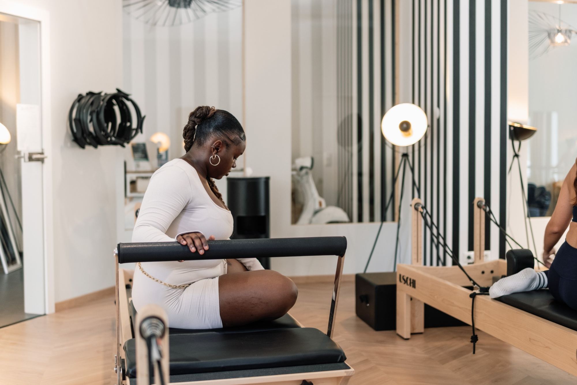 A woman getting comfortable on a Reformer before class