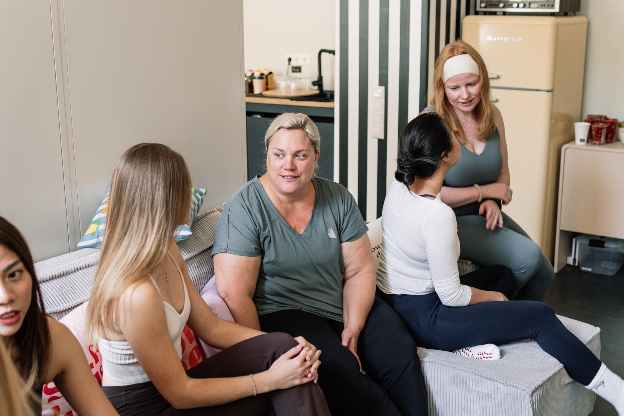 Women of different ages and bodies chatting and laughing together in the studio lounge