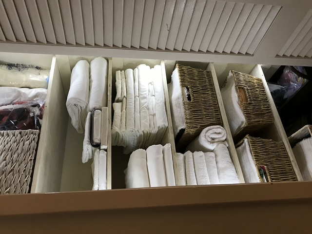 An organized linen closet with linens folded and stacked in storage
