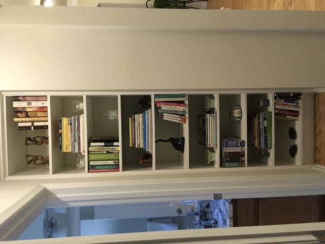 An organized home bookshelf with books and pieces arranged by size