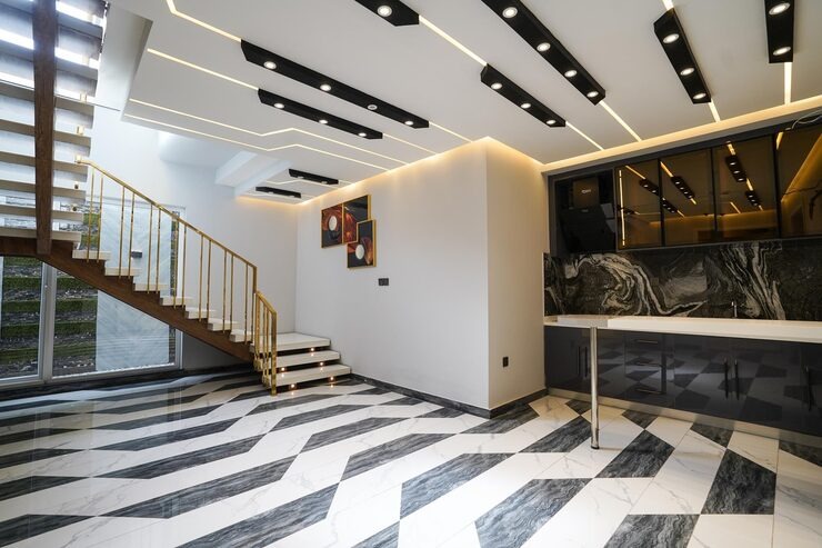 Architecture d'intérieur haut de gamme montrant des finitions en marbre noir, un éclairage encastré linéaire et un escalier élégant dans une maison moderne et spacieuse.