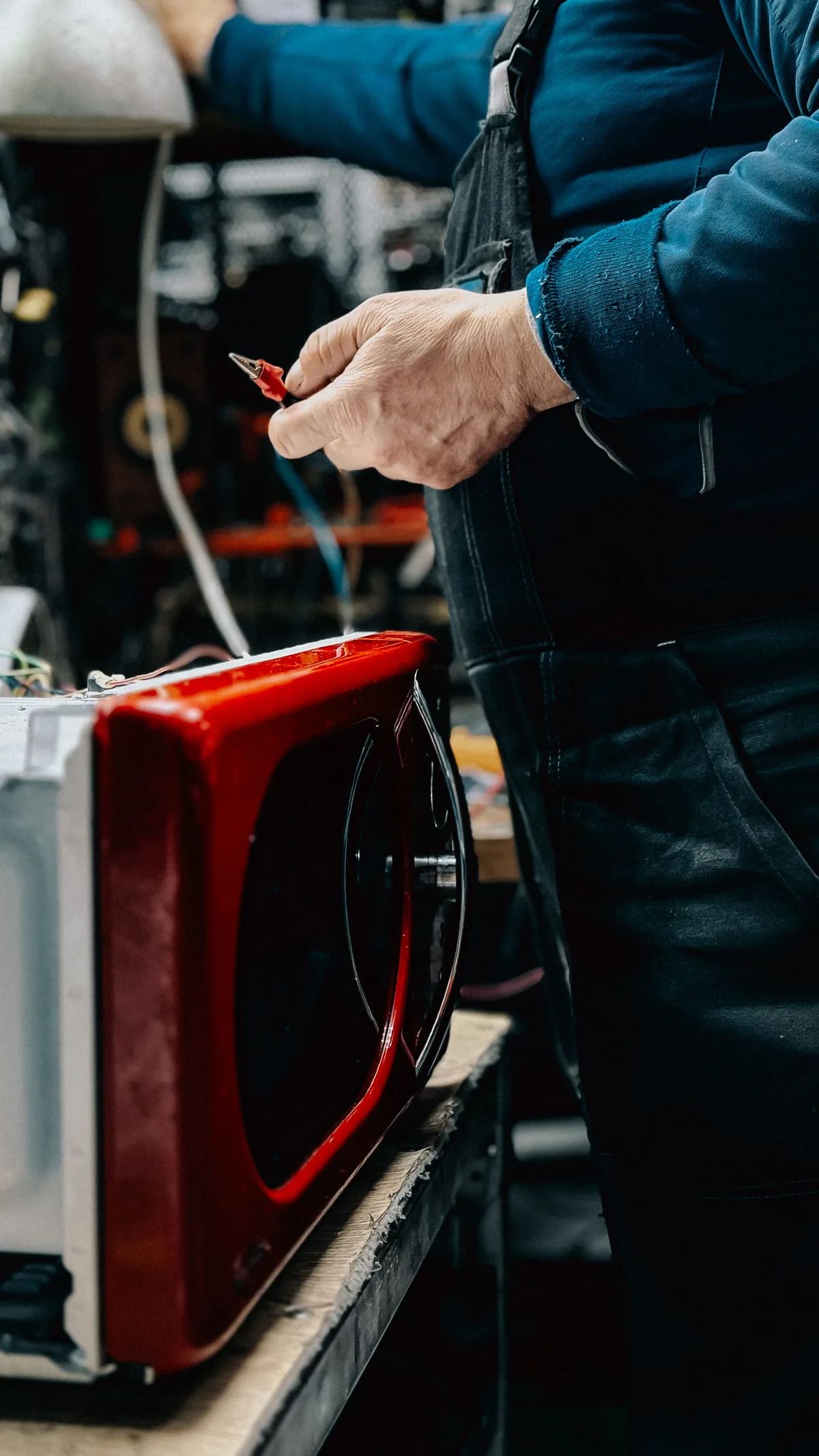 Appliance repair technician testing a microwave control circuit on the bench