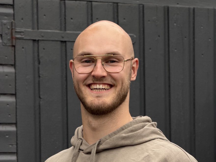 Sander, mede-oprichter van FORTIVS, lachend voor een donkergrijze deur.