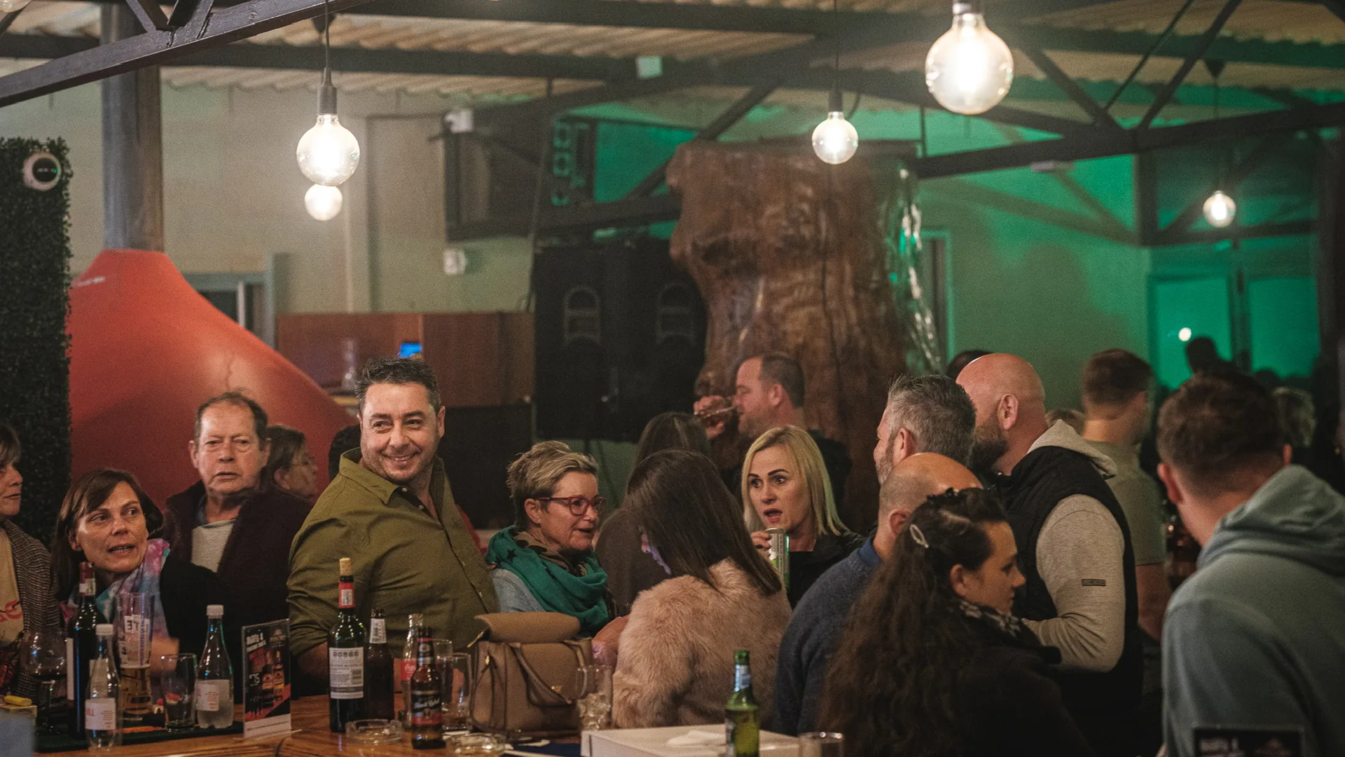 Long tables of guests under hanging lights inside Breezy's
