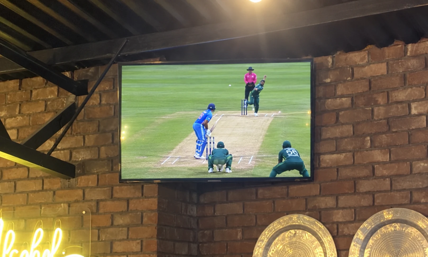 Cricket match on a TV on the brick wall at Breezy's