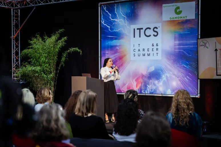 Sara presenting to a seated audience at a summit