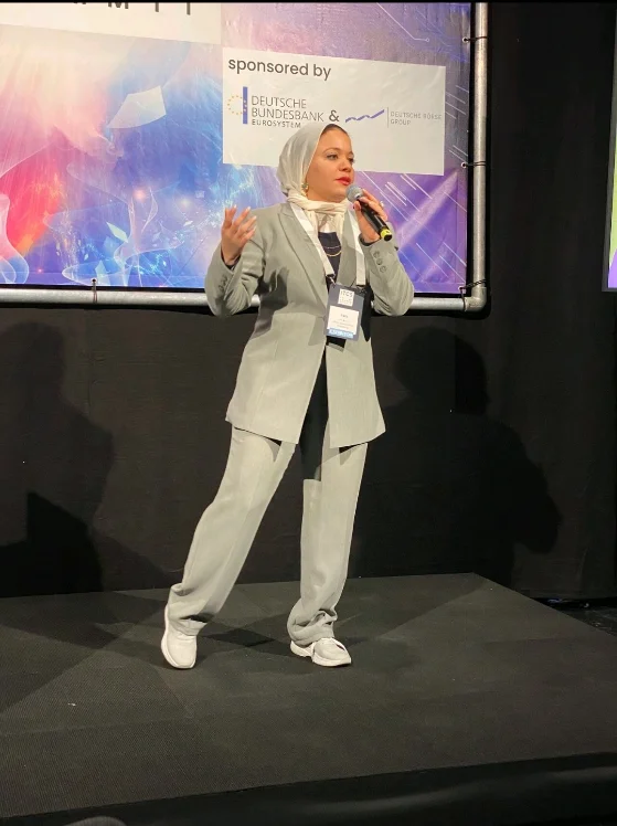 Sara speaking on stage with a microphone