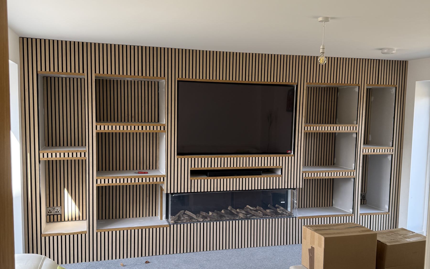 Full-width slatted media wall with lit alcoves