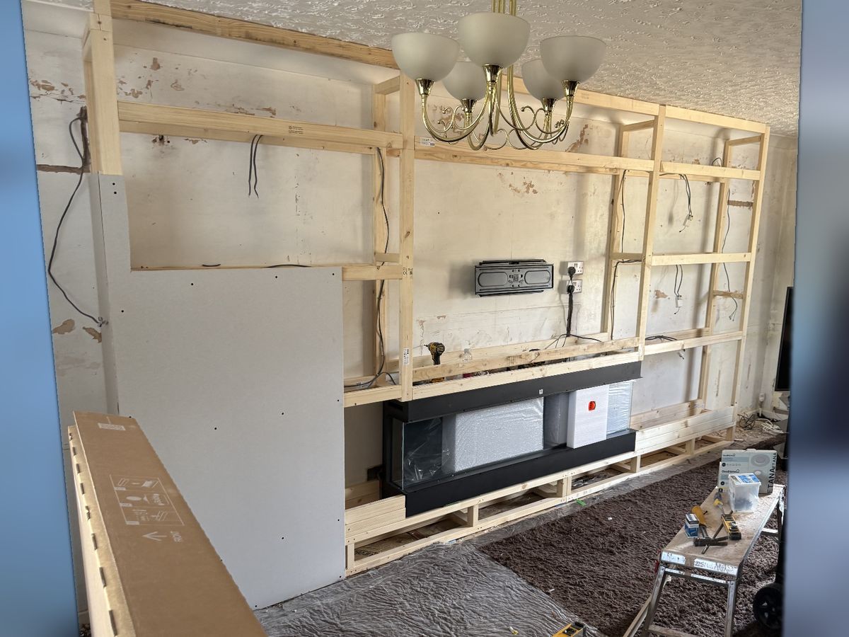 The same wall as a bare timber frame with the fire box and cables in place