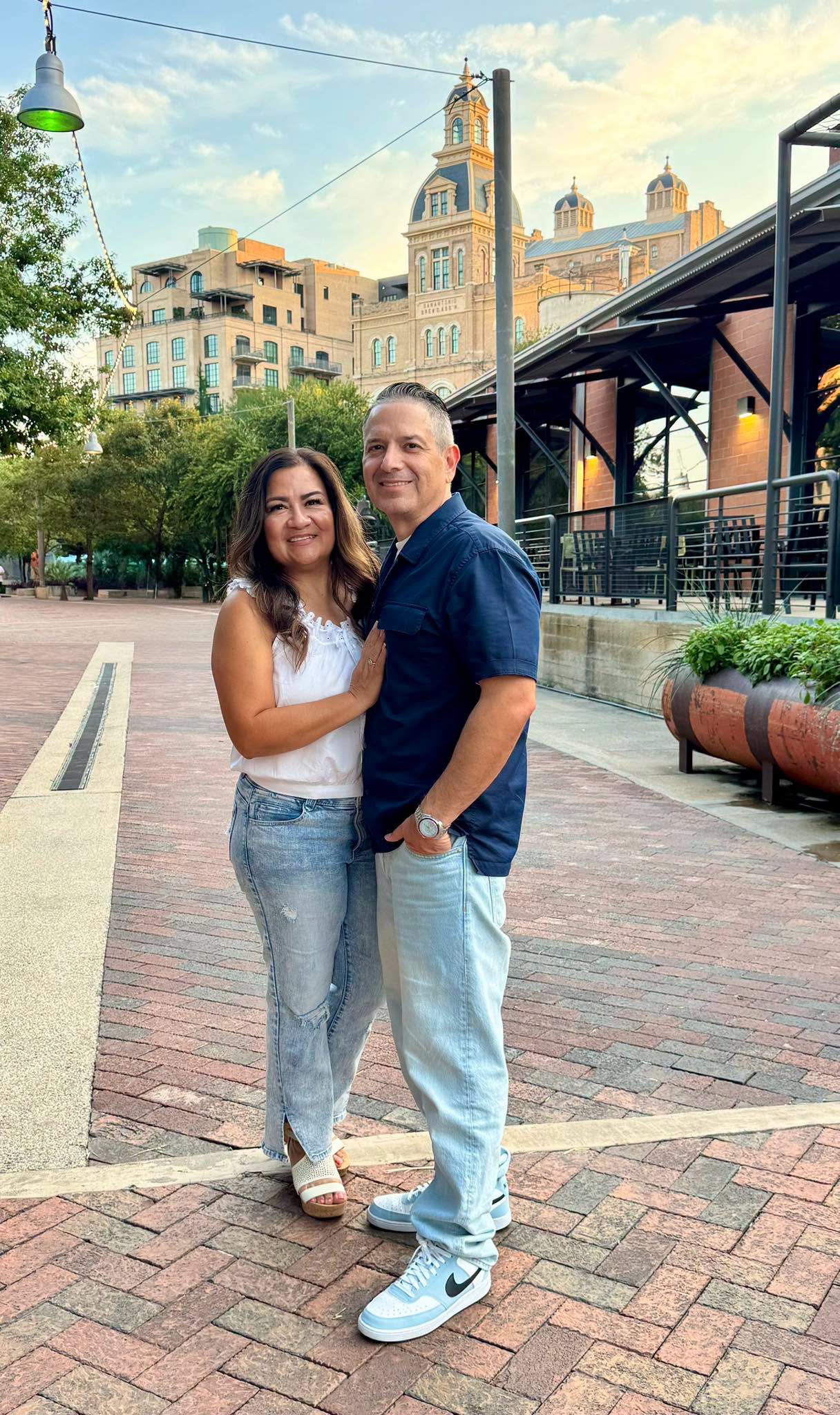 A couple standing together on a brick plaza at golden hour