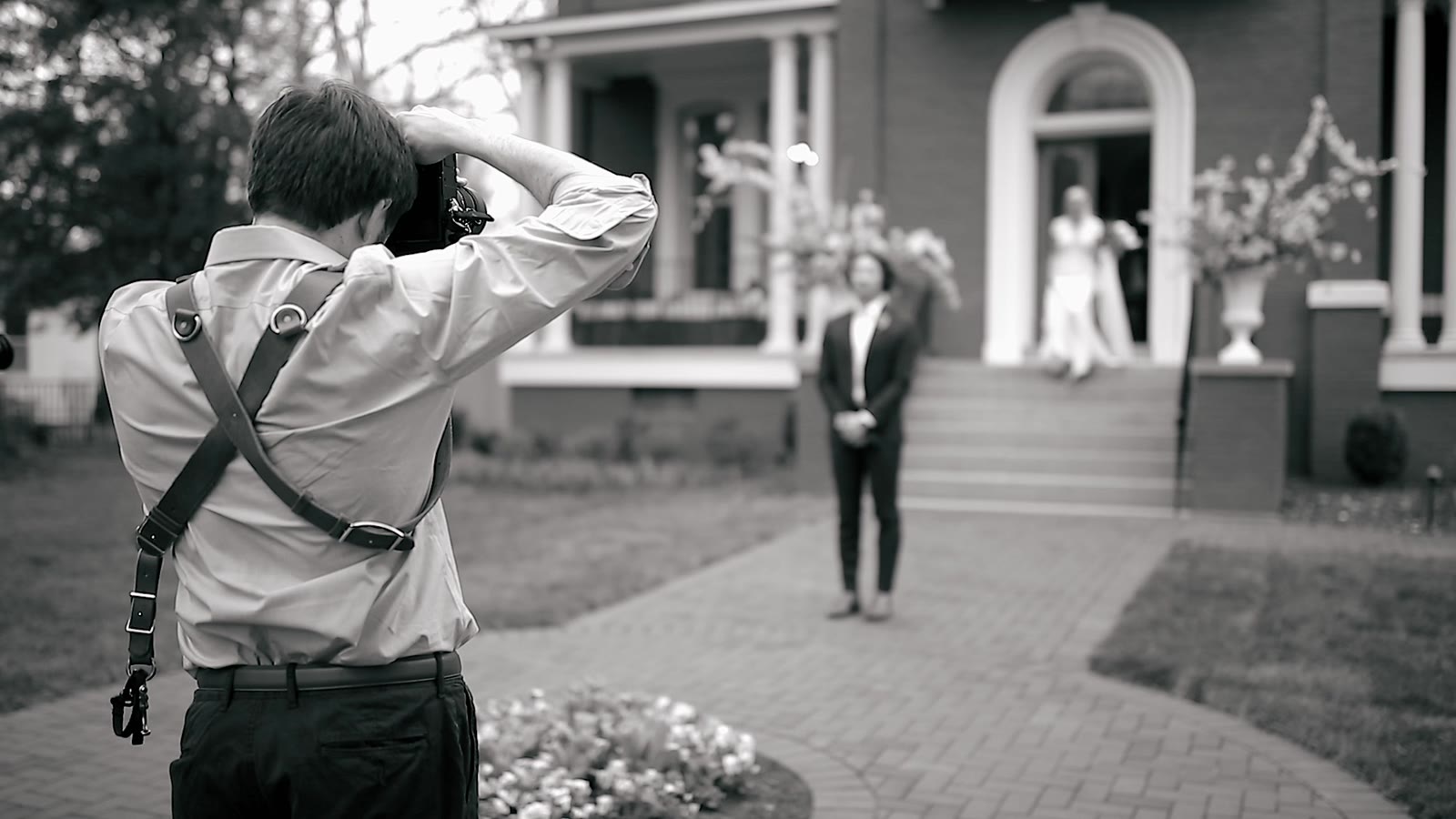 Ian photographing a bride on the steps while Radhika watches the room
