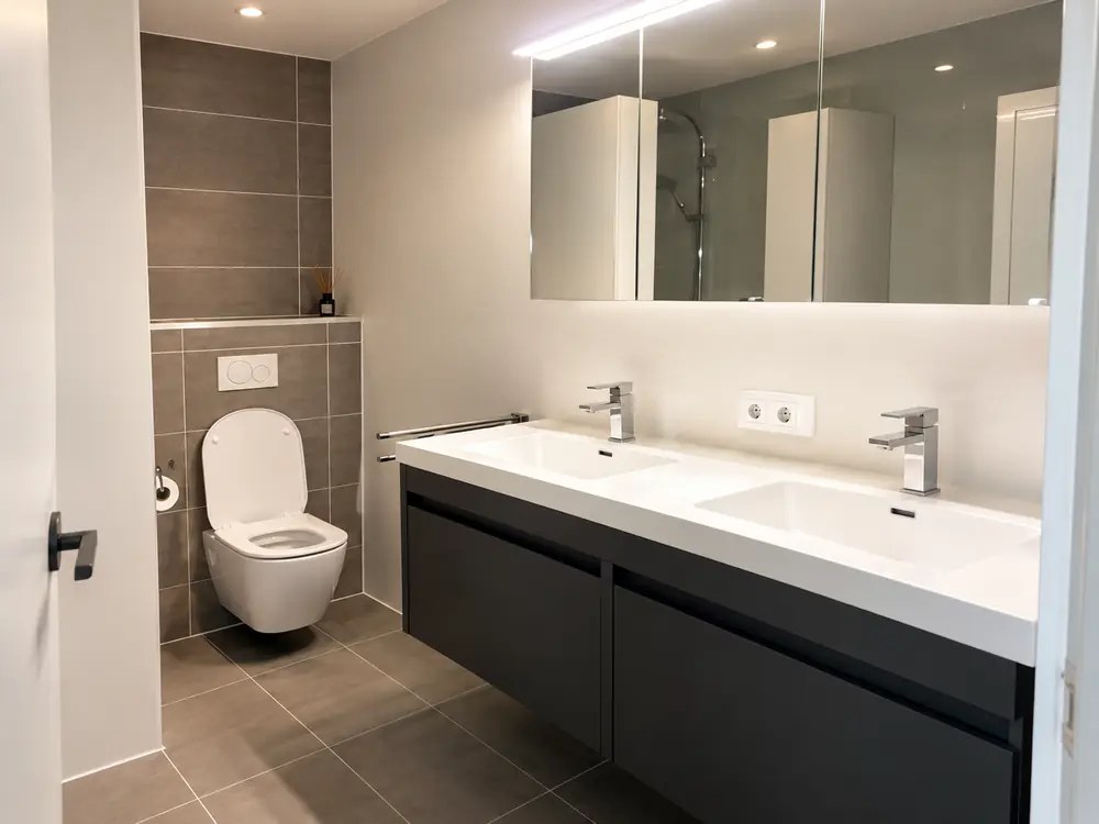 Gerenoveerde badkamer met hangtoilet en dubbele wastafel in Rotterdam