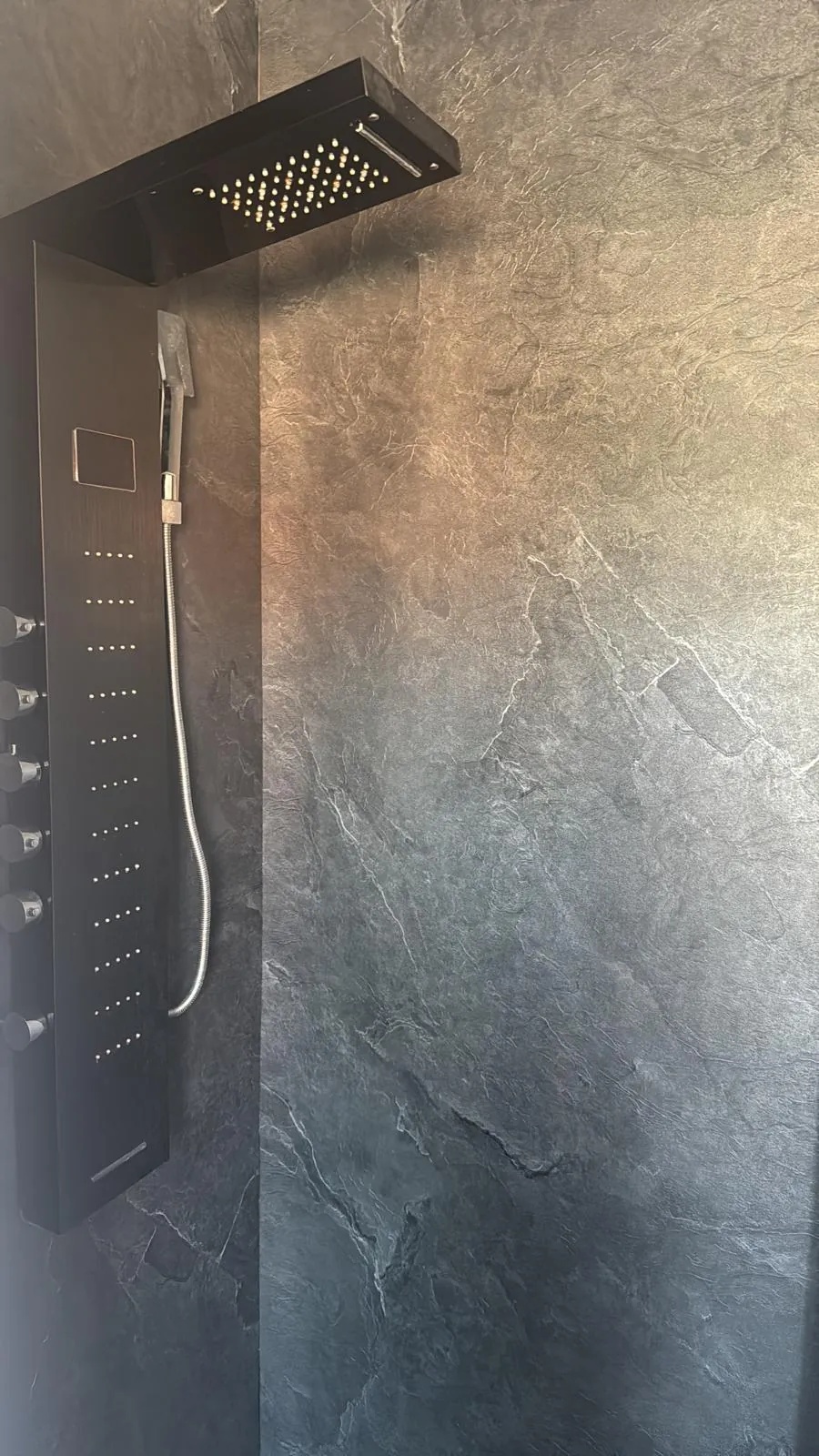 Zwart douchepaneel met regendouche op een stenen douchewand in de regio Rotterdam