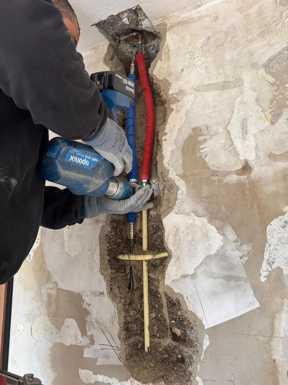 Nieuwe waterleidingen worden geperst in een sleuf in de muur in de regio Rotterdam