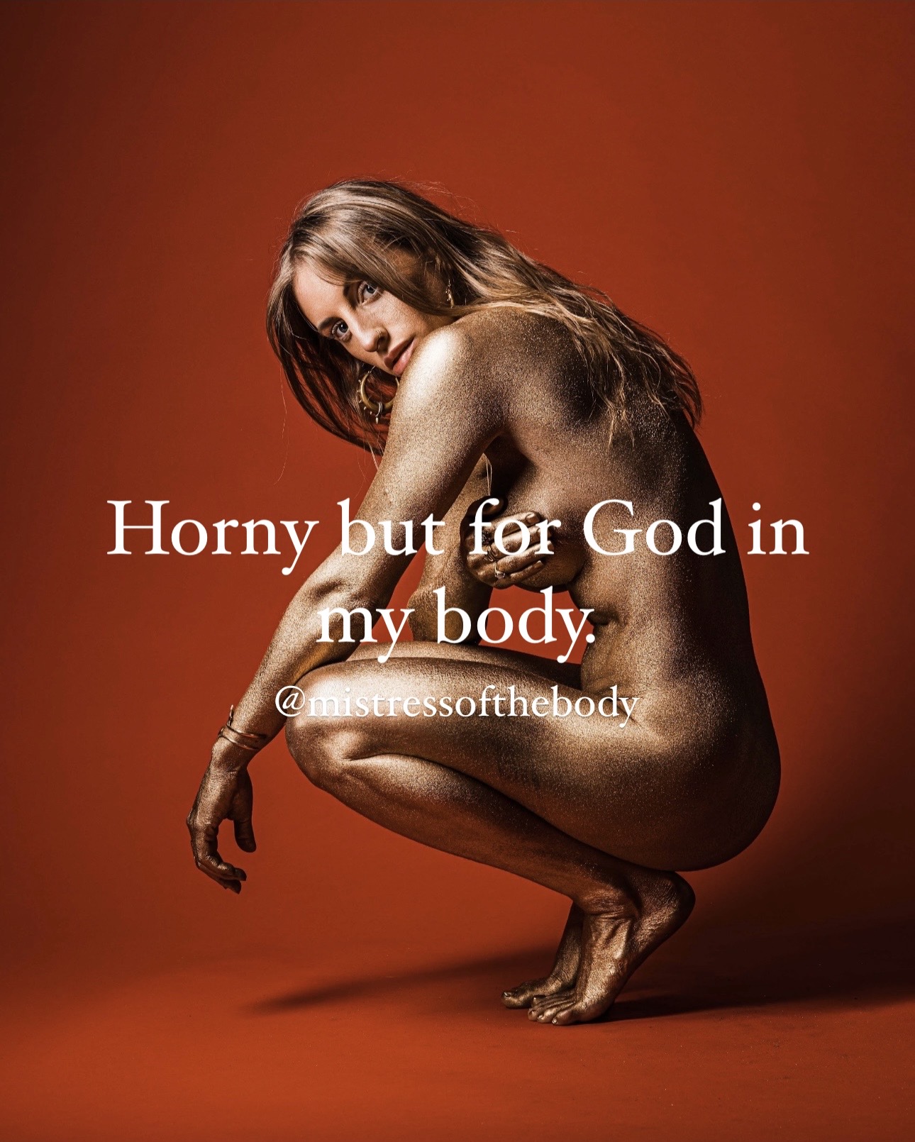 A woman seated nude with her knees drawn up and her skin painted metallic gold on a burnt-orange ground, looking back over her shoulder, captioned: horny but for God in my body