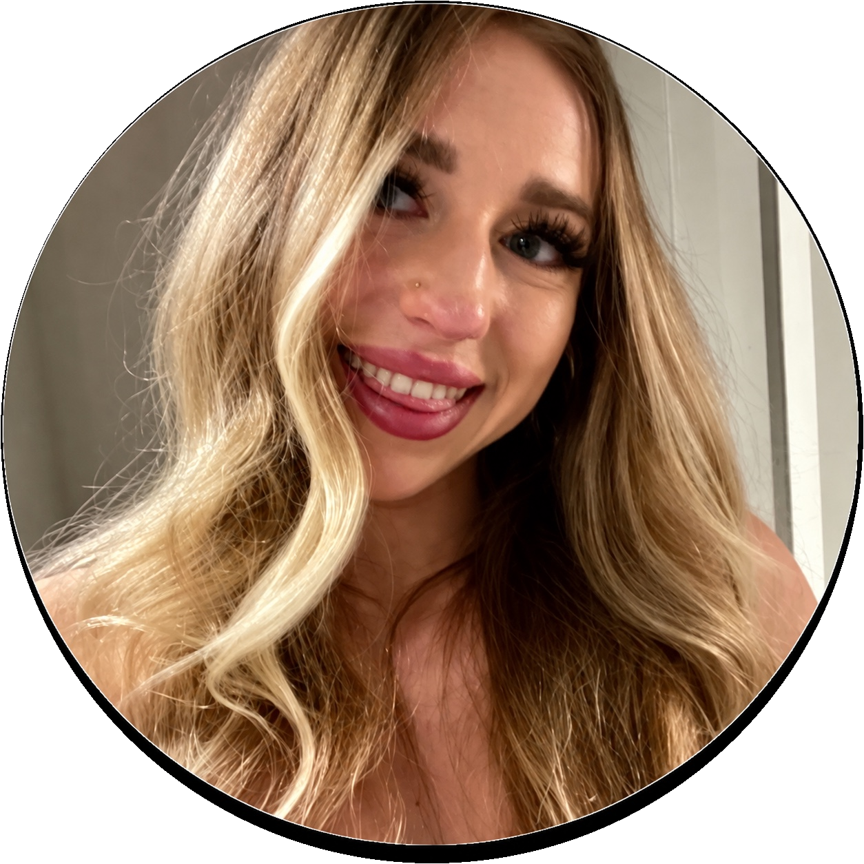 Olivia G, a smiling woman with wavy blonde hair, berry lipstick and bare shoulders