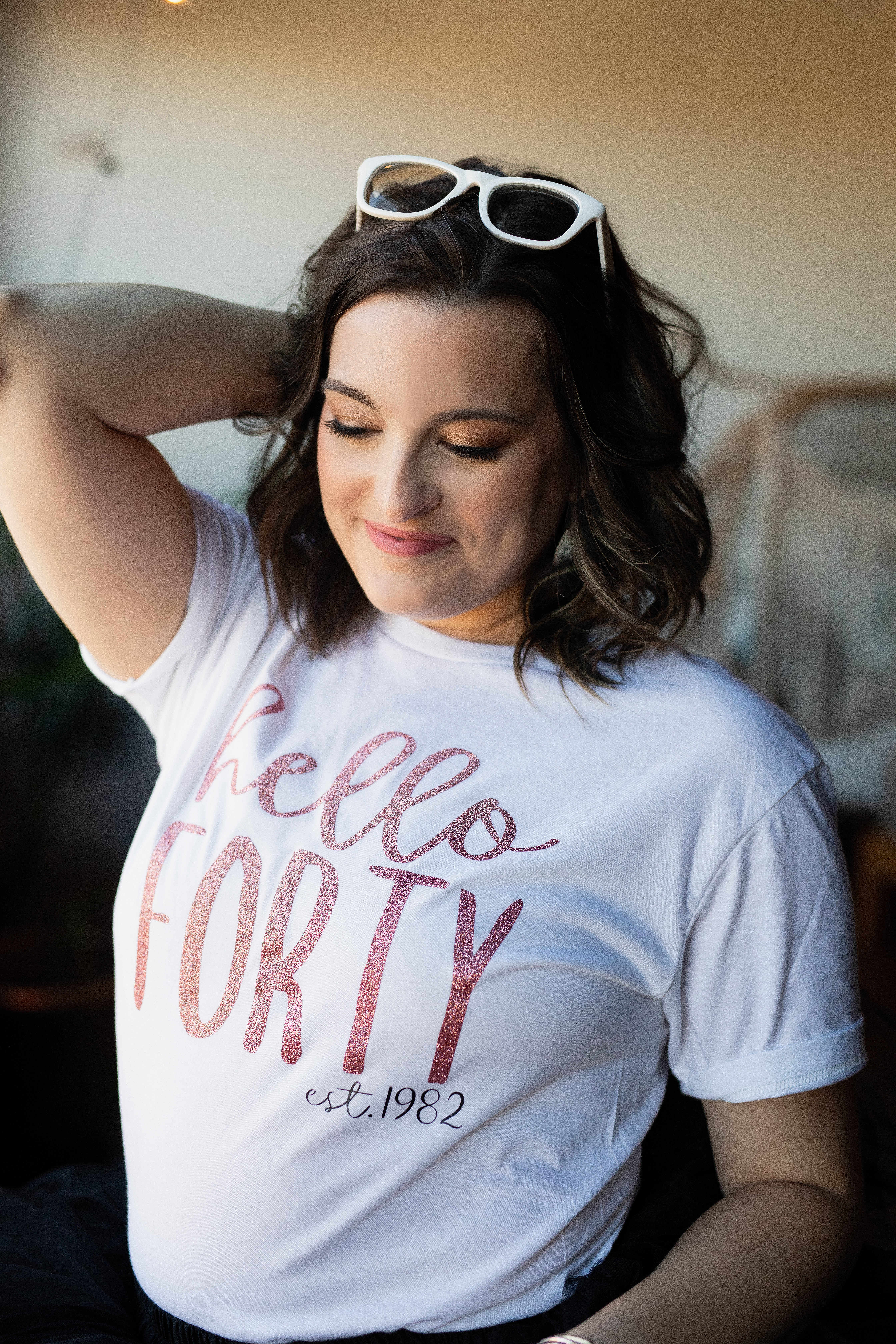 Close-up portrait of a woman in a “Hello Forty” shirt smiling softly during a 40th birthday photoshoot. Close-up portrait of a woman in a “Hello Forty” shirt smiling softly during a 40th birthday photoshoot.
