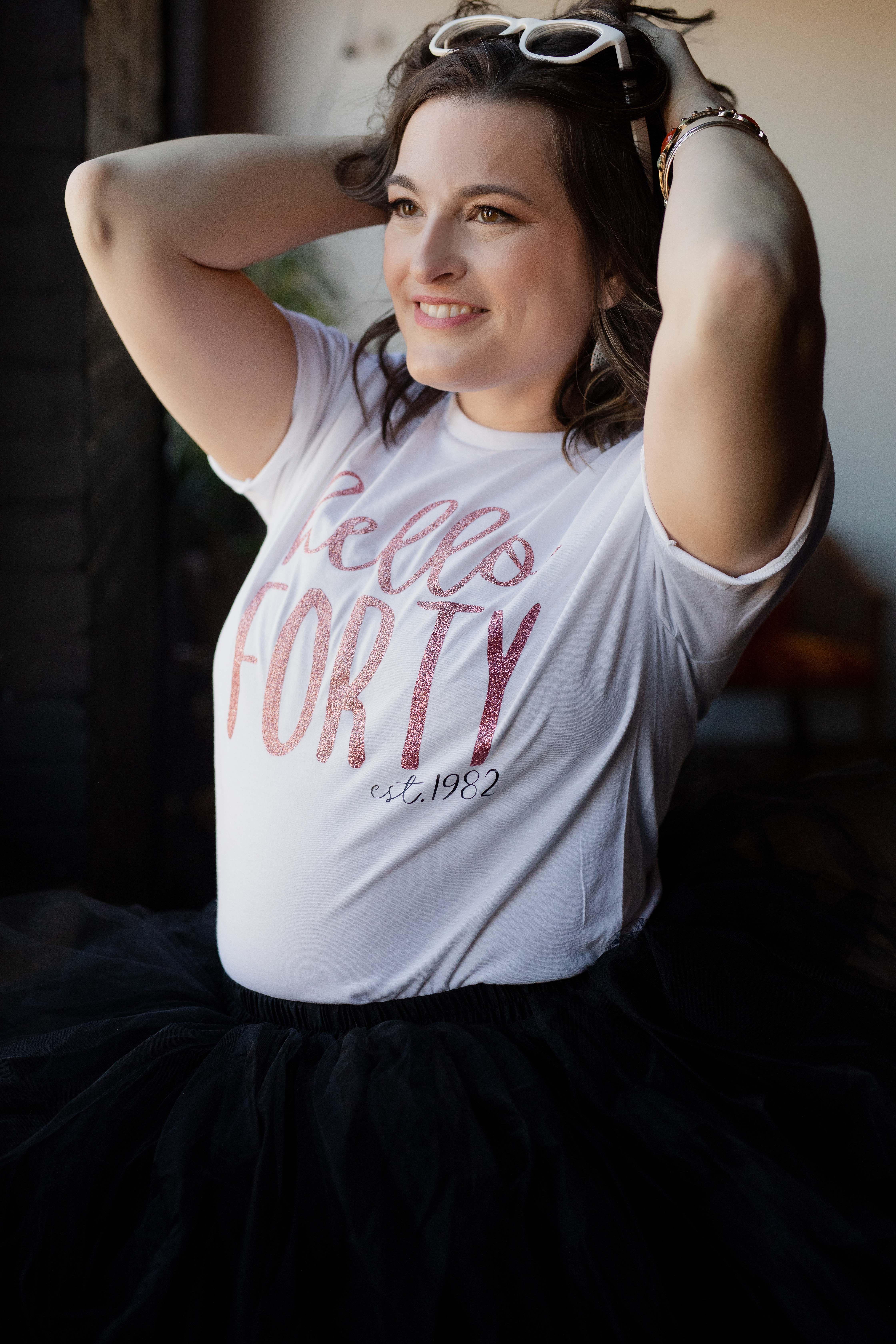 Close-up lifestyle image of a woman celebrating turning forty wearing a “Hello Forty” t-shirt. Close-up lifestyle image of a woman celebrating turning forty wearing a “Hello Forty” t-shirt.