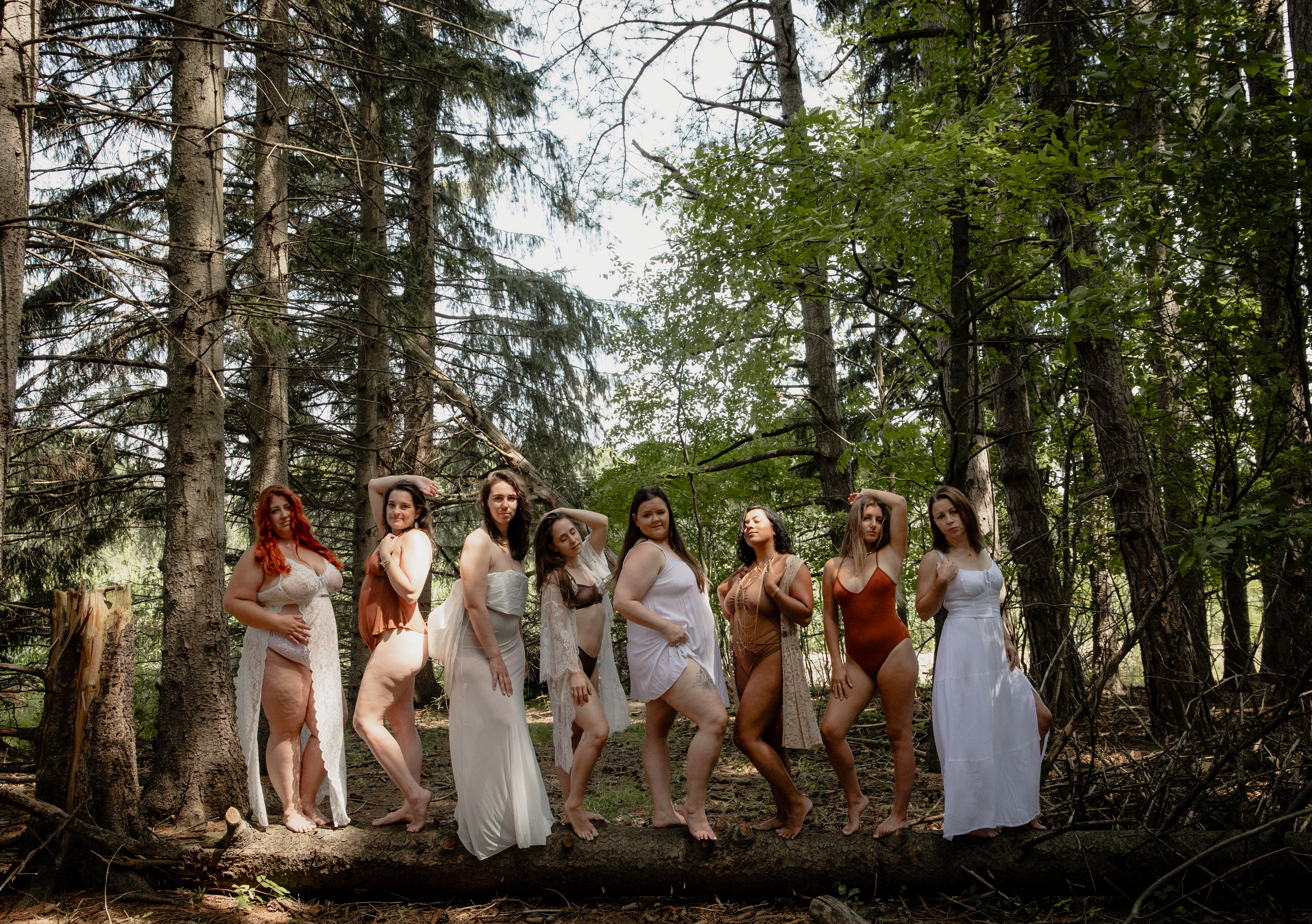 Women standing together among tall trees during a group outdoor boudoir photoshoot.